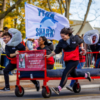 Ball State students pushing a bed down Riverside while racing in the Bed Race during Homecoming week