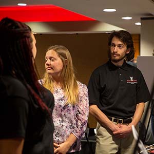 Three students talk at an event. 