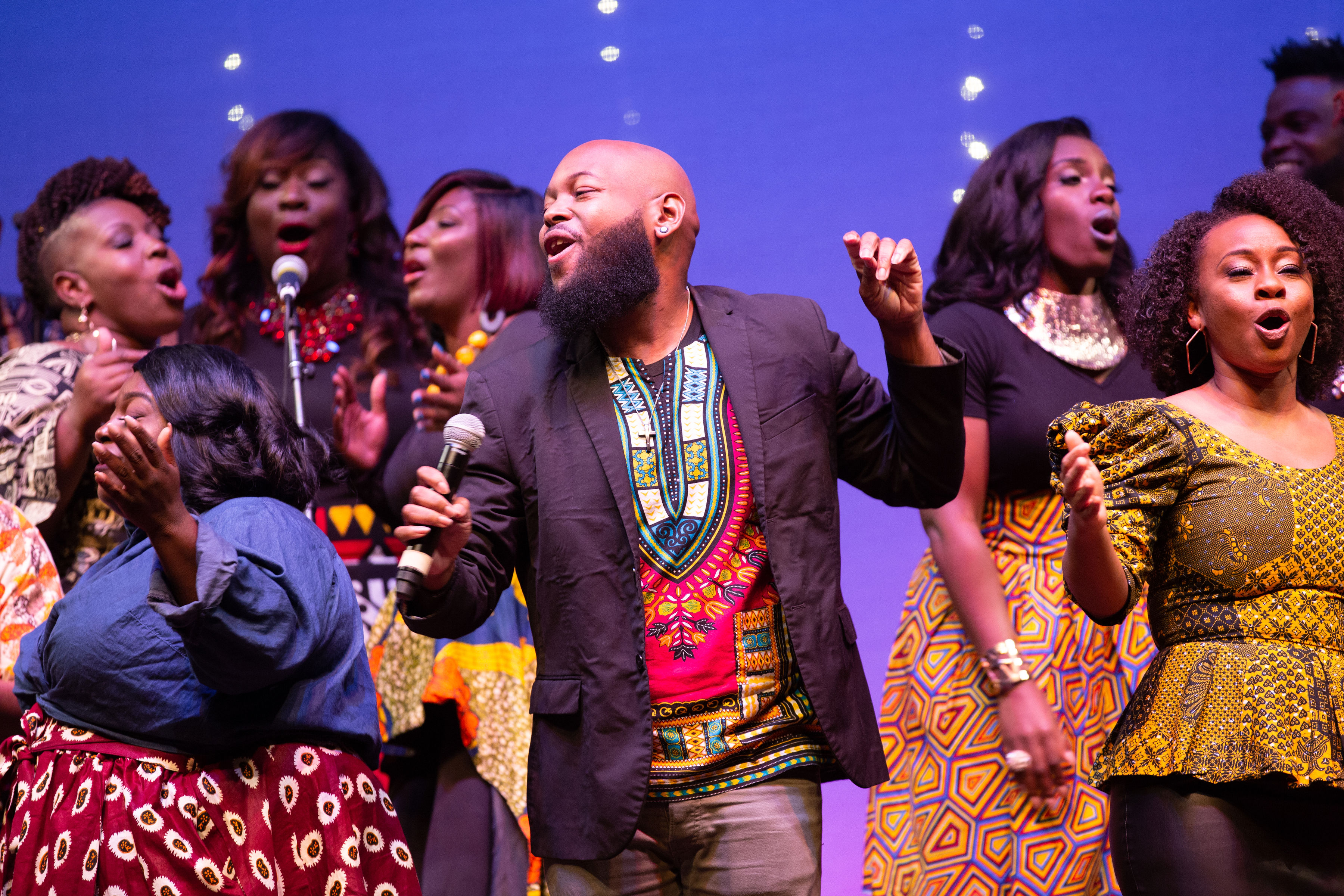 Trey McLaughlin and the Sounds of Zamar perform onstage wearing colorful clothing in various African prints