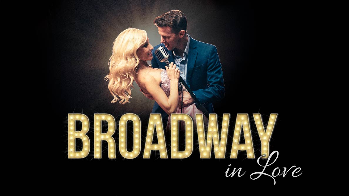 Libby Servais and Stephan Stubbins pose lovingly with a logo in marquee lighting. Logo text reads, "Broadway in Love."