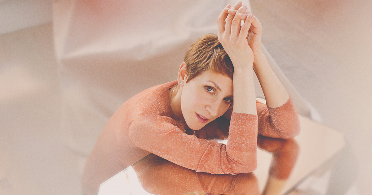 Artist Stacey Kent, a white woman with short, brown hair wearing a brown sweater and a red lipstick, poses for a photo