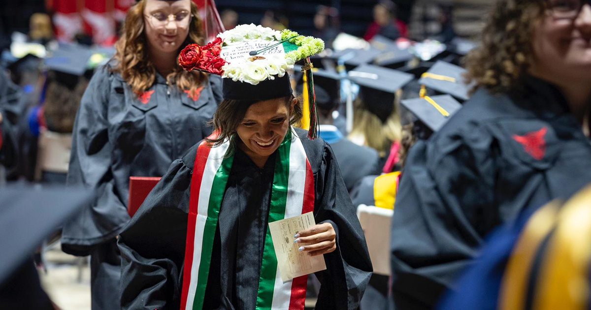 Graduate smiling while walking to get their diploma