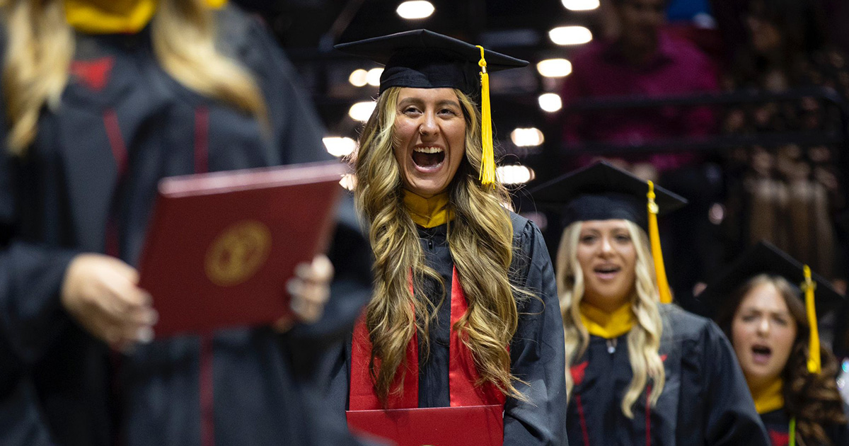 Graduate smiling widely at camera while holding diploma