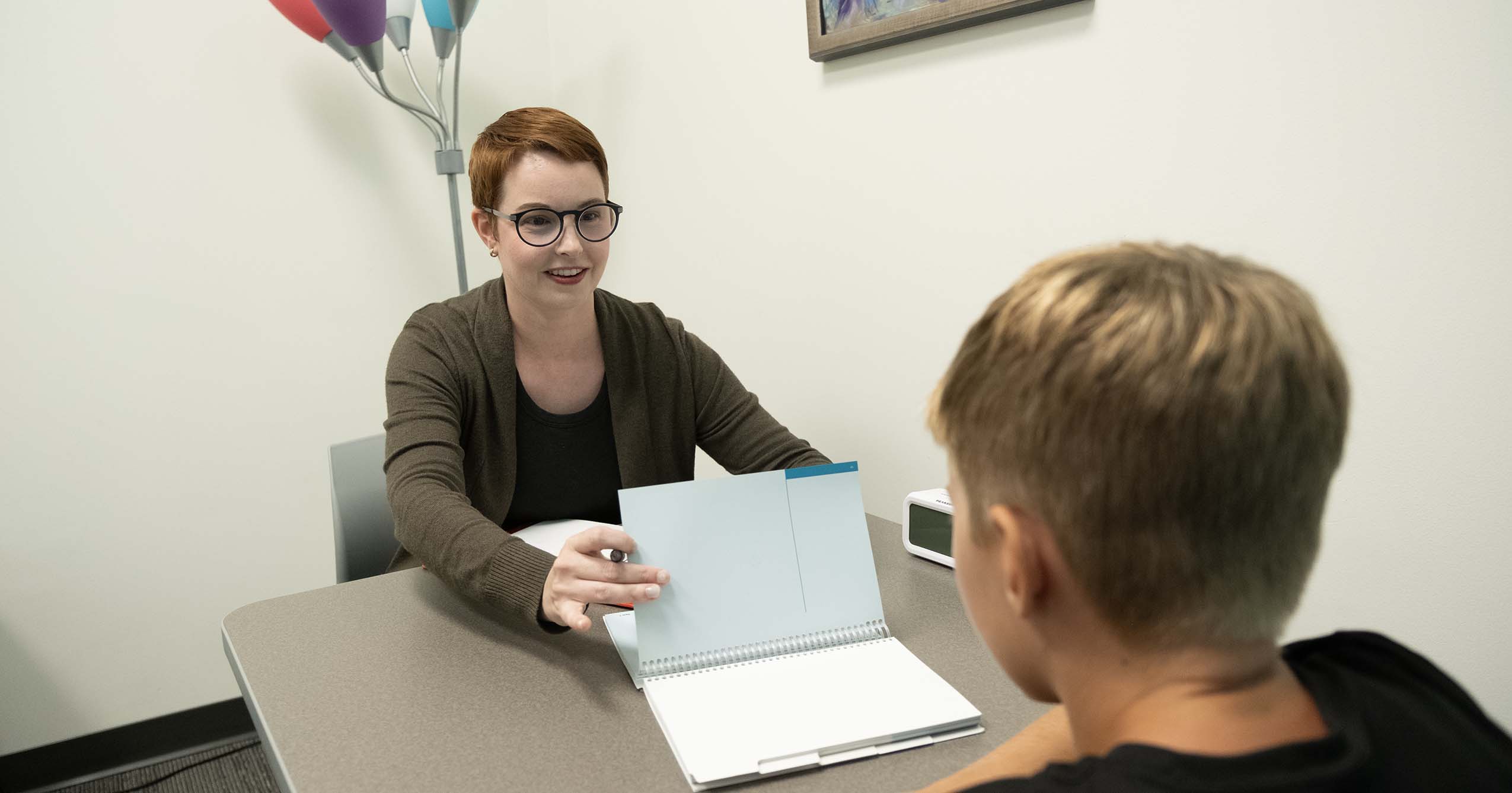 A clinician sits across from a young client during a one-on-one session in a Ball State University Interprofessional Community Clinic.