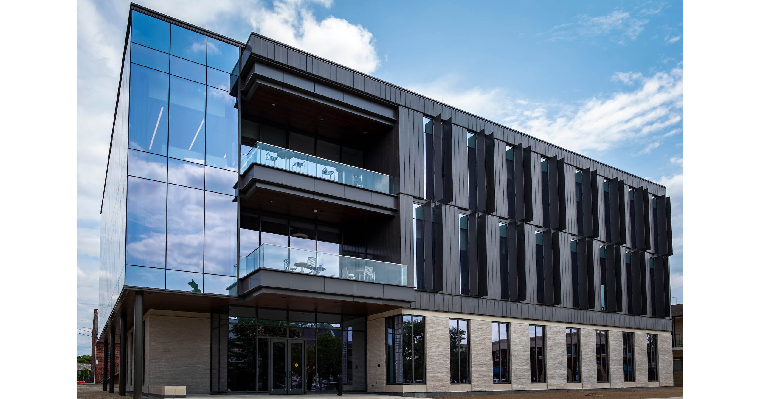 Exterior of Ball State University’s Center for Innovation and Collaboration, a three-story building with large glass windows, dark vertical panels, and outdoor terraces.