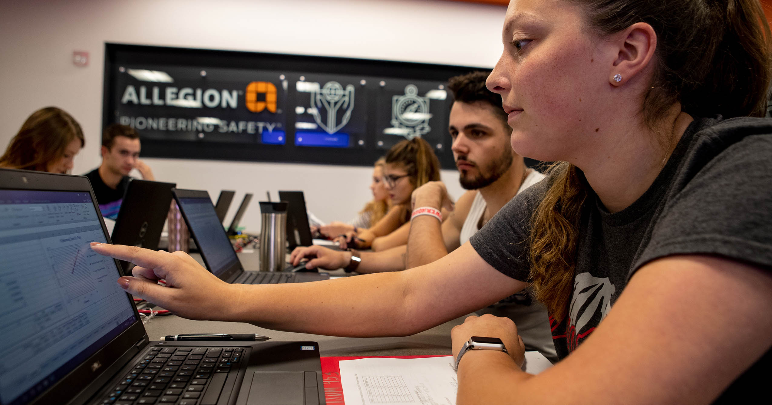 Ball State students work on laptops during a Logistics and Supply Chain Management class, with one student pointing to data on her screen.