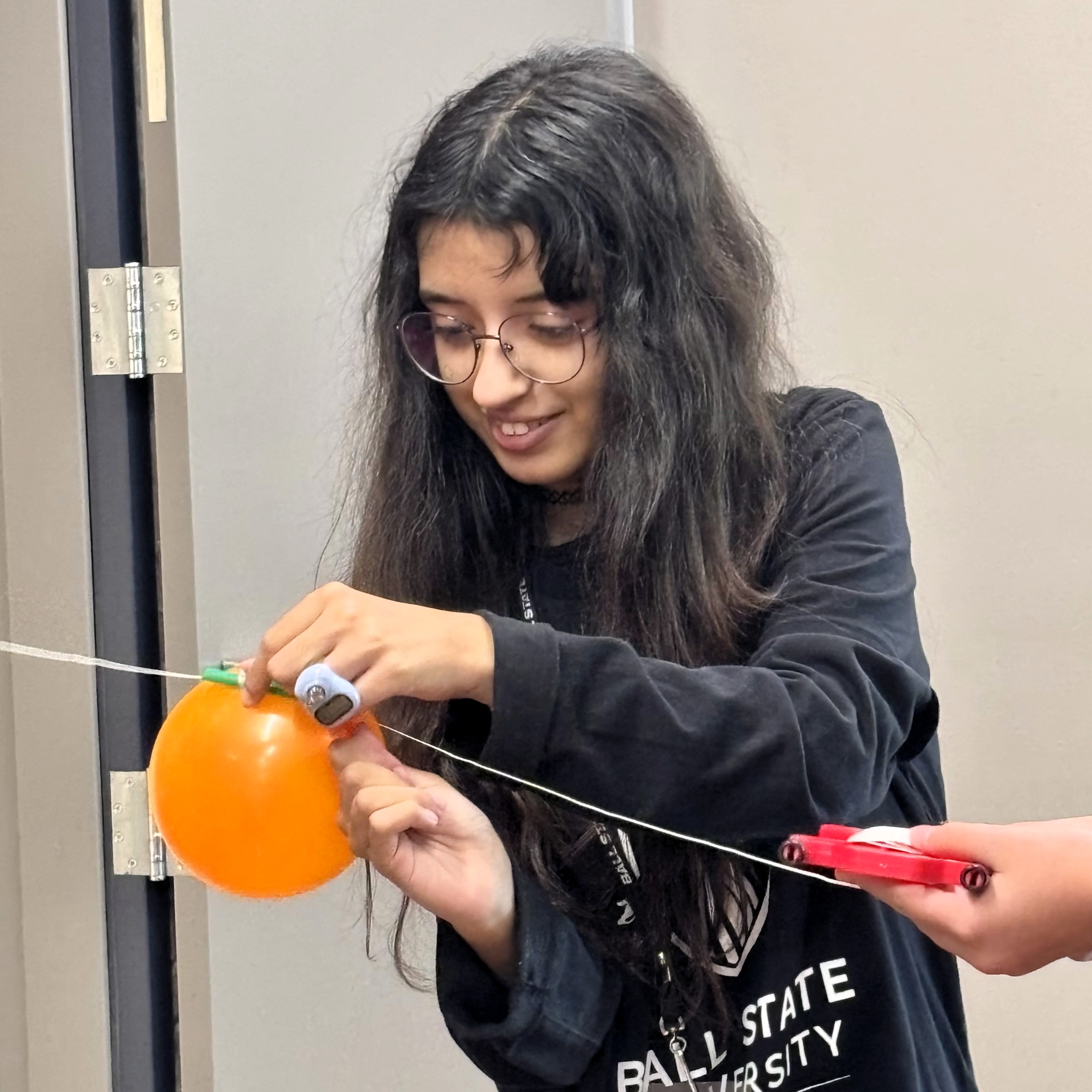 Planetarium worker Sara participating in a balloon rocket activity in the planetarium lobby.