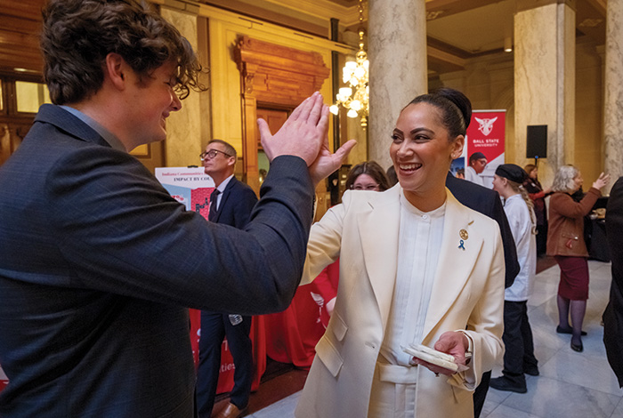 A student and a woman in professional attire high-five at a Ball State event inside the Indiana Statehouse.