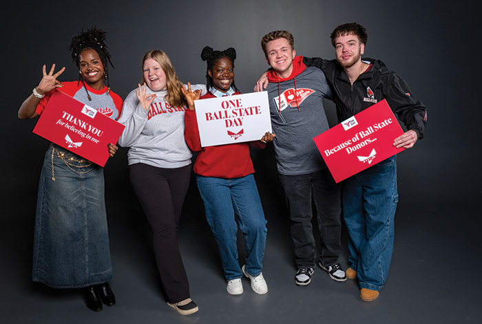 Five Ball State students pose together holding signs thanking donors and celebrating One Ball State Day.