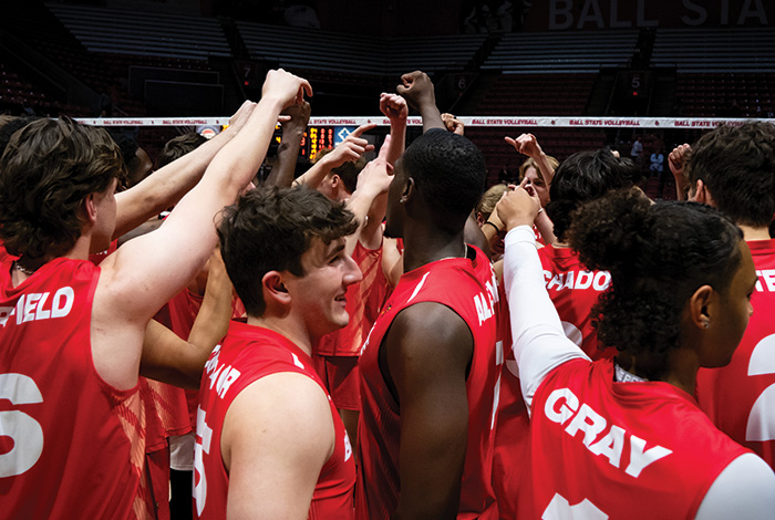 Ball State men’s volleyball players huddle together on the court before a match.