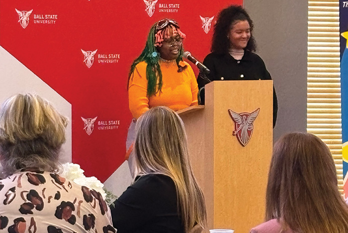 A speaker addresses attendees from a Ball State podium while another person stands beside her.
