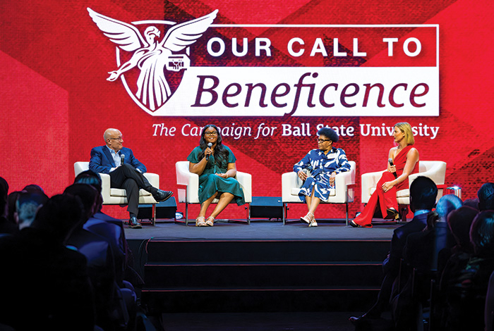 Four panelists speak onstage beneath a large “Our Call to Beneficence” campaign banner before a seated audience.